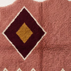 Angled view of diamond medallion displaying wool pile depth and colour contrast between rose field and burgundy medallion