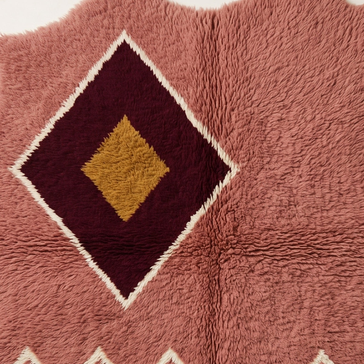 Angled view of diamond medallion displaying wool pile depth and colour contrast between rose field and burgundy medallion