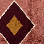 Detailed shot of centred gold diamond within burgundy medallion showing hand-knotted wool construction