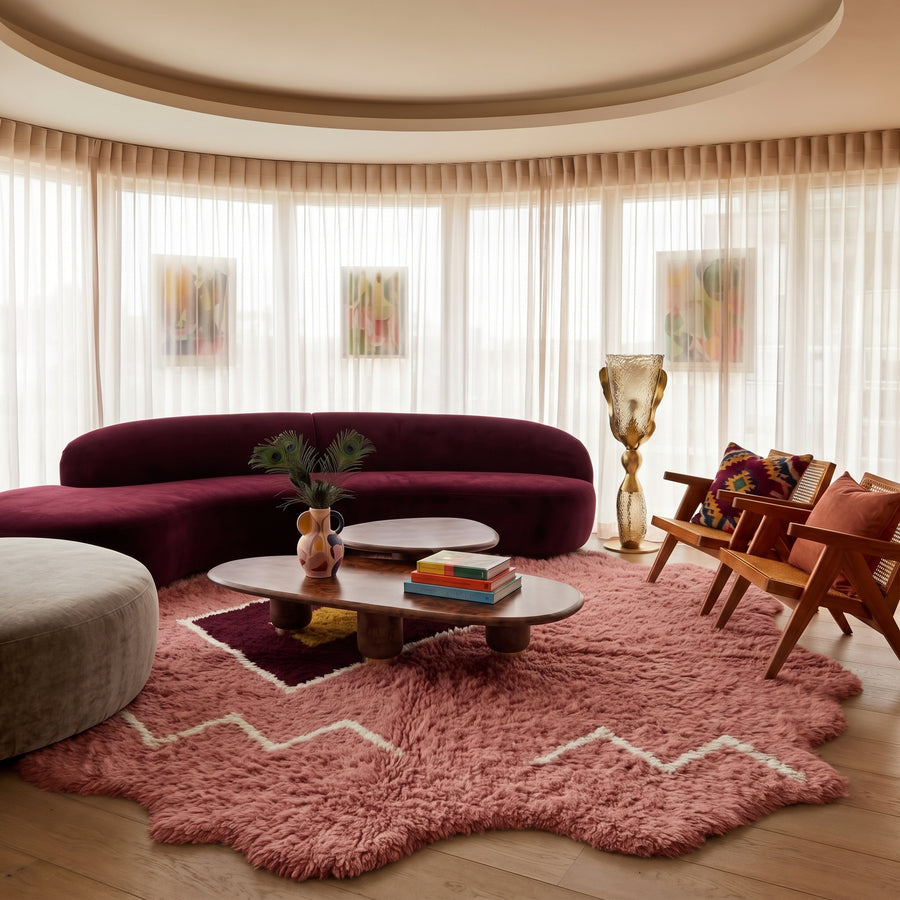 Rose Beni Ourain rug with diamond medallion placed in modern living room with burgundy curved sofa and wooden chairs