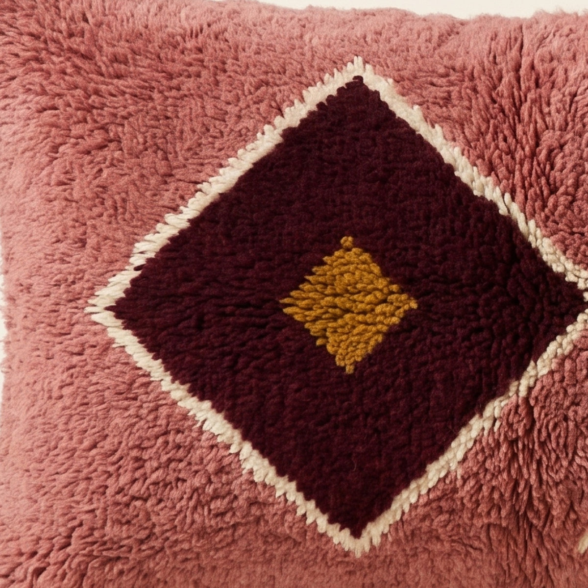 Side view of the Lalla Moroccan pillow showing its rose and burgundy wool pile