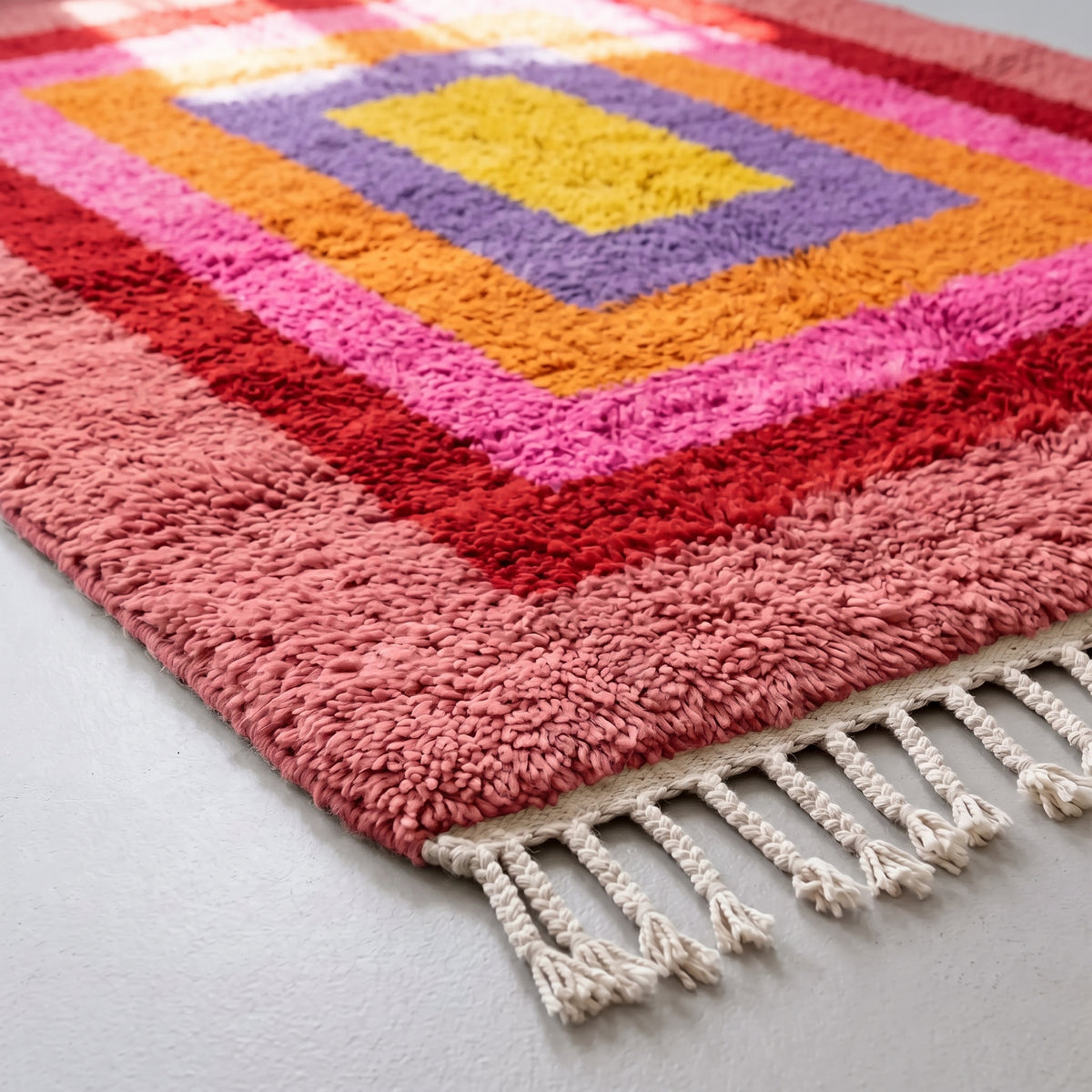 Angled pile detail of Menna Azilal rug showing soft wool texture and colour transitions across nested rectangle bands