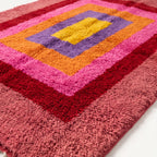 Close-up texture detail of Menna rug showing hand-knotted wool pile in magenta, gold, purple and red layers with dimensional depth