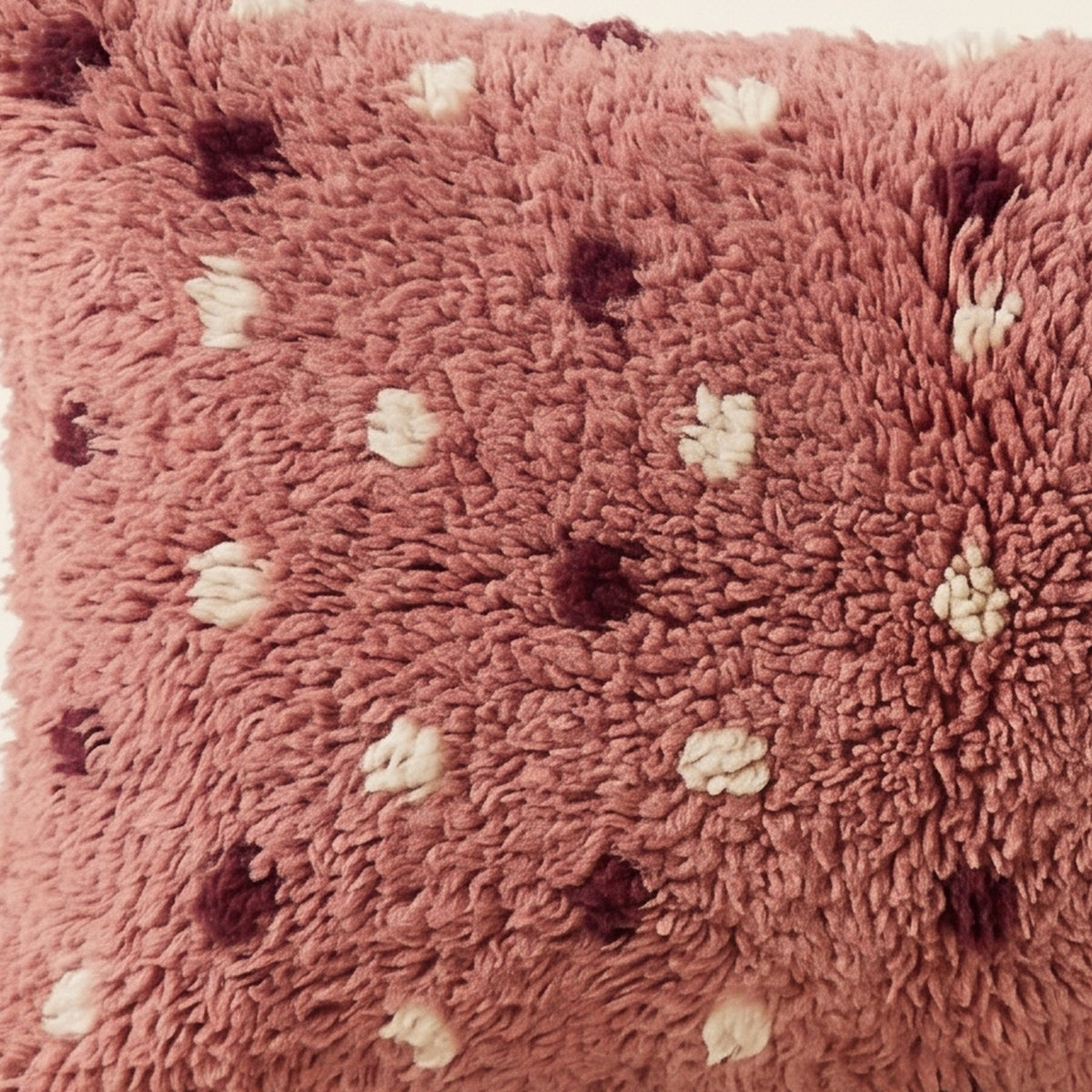 Side view of the Tamazight Moroccan pillow showing its rose and plum wool pile