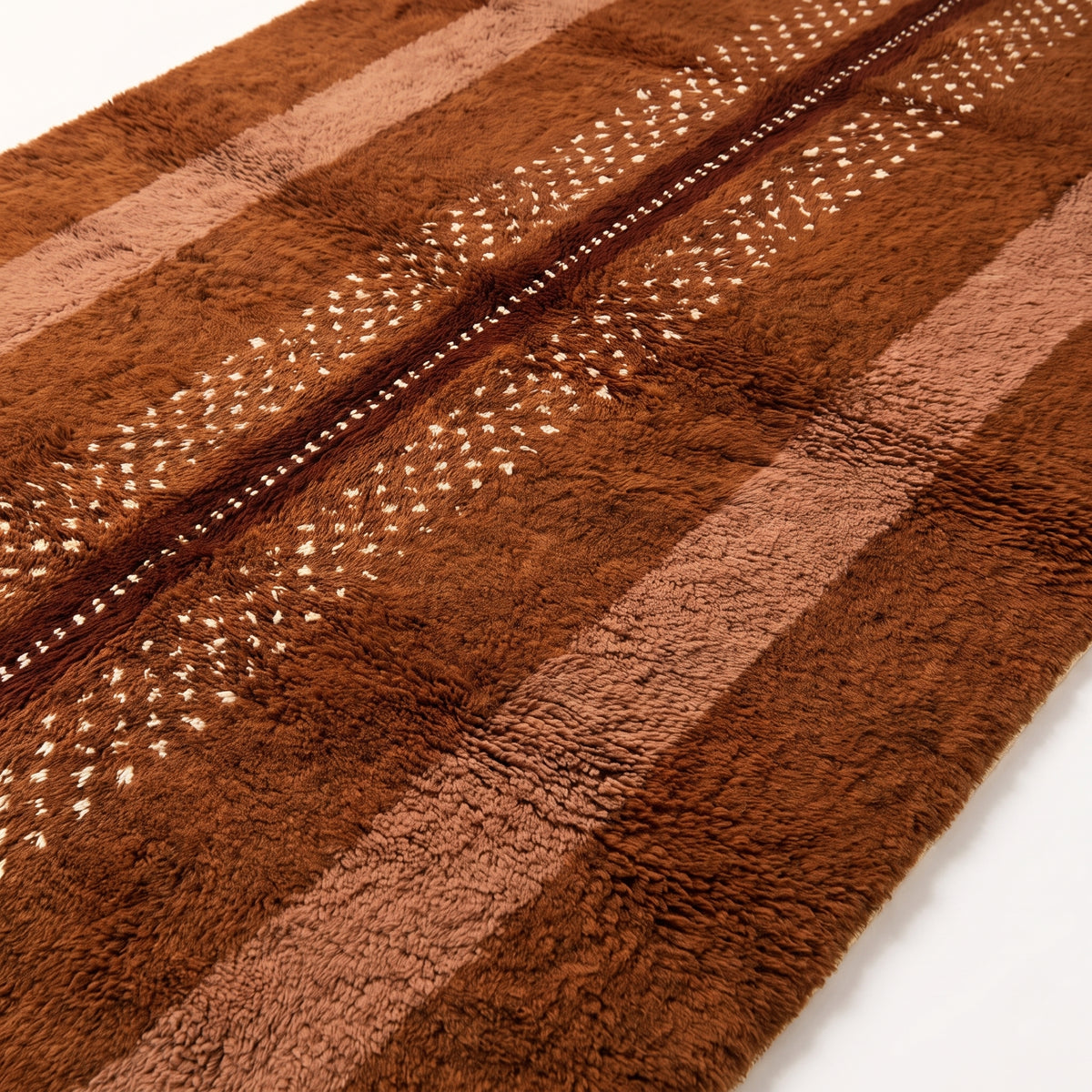 Close-up of rust and fawn striped pattern with white scattered motifs and pile texture