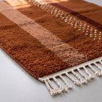 Angled detail of thick soft pile showing rust, fawn and white scattered motifs
