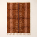 Rust and fawn Beni Ourain rug with scattered white motifs and dark brown centre line, flat lay view