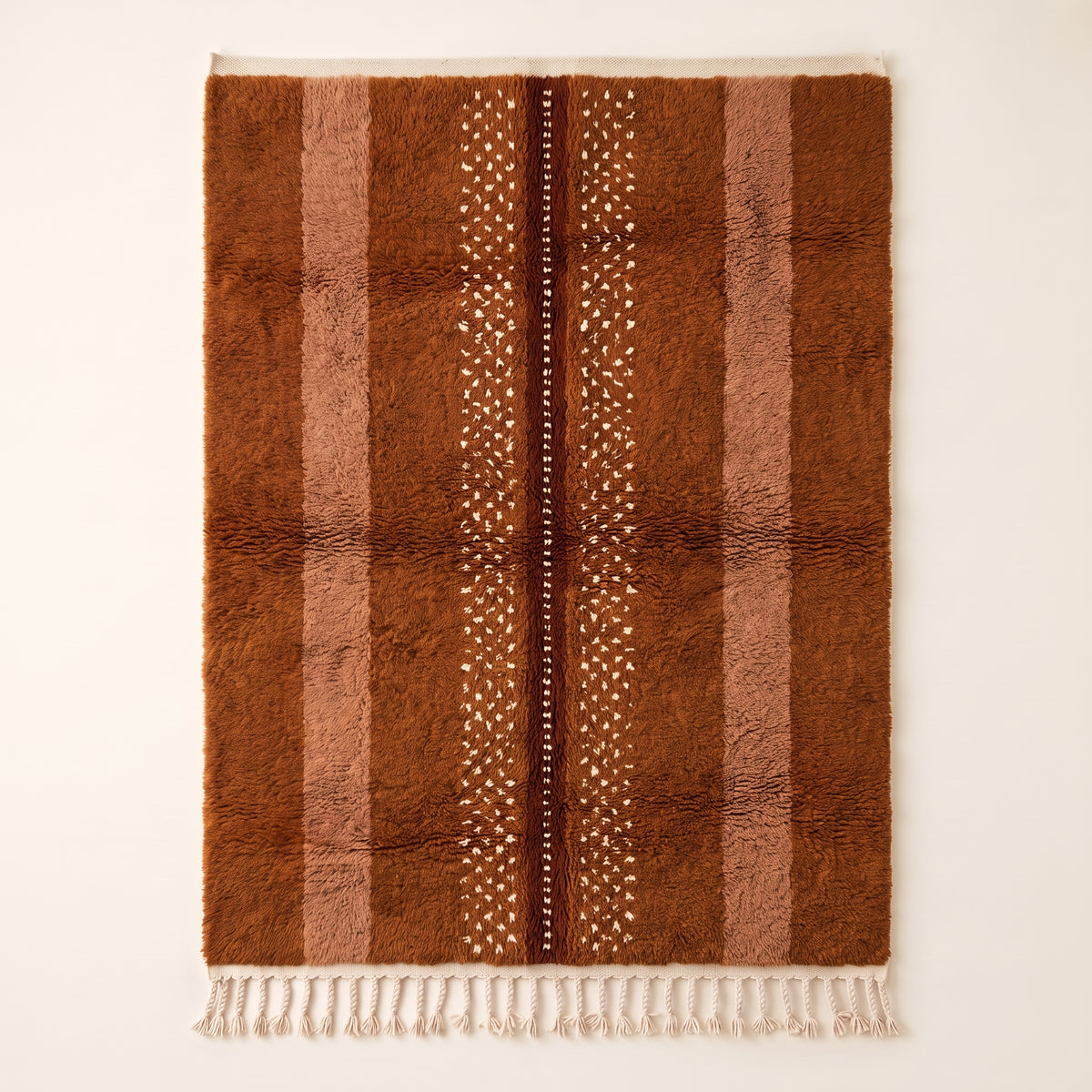 Rust and fawn Beni Ourain rug with scattered white motifs and dark brown centre line, flat lay view