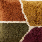 Side view of the Tafsut Moroccan pillow showing its rust, mustard and navy wool pile