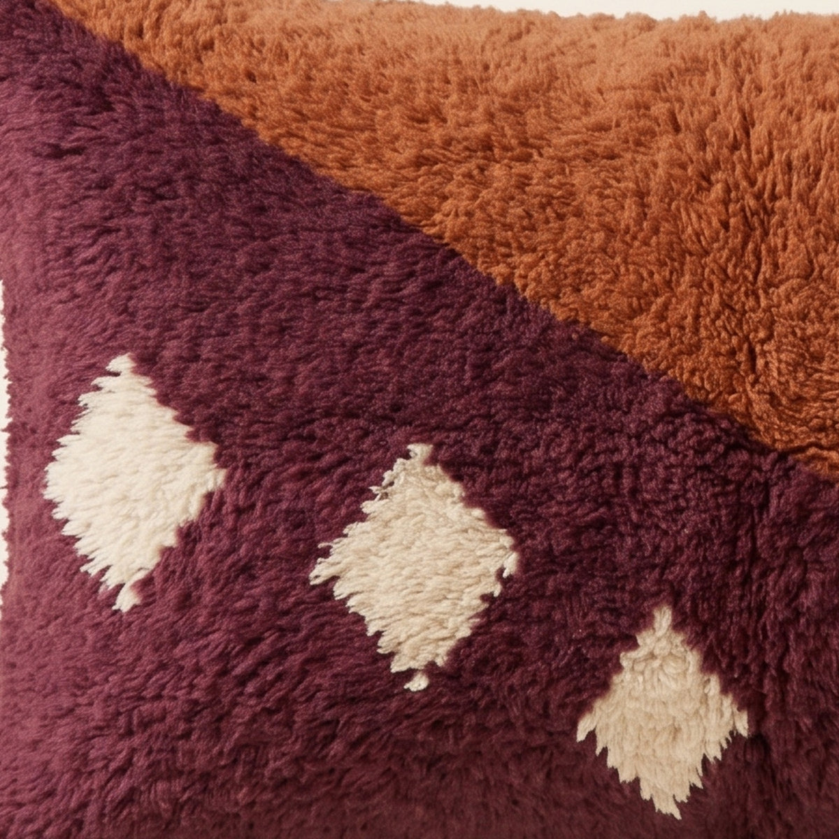 Side view of the Tamurt Moroccan pillow showing its rust and plum wool pile