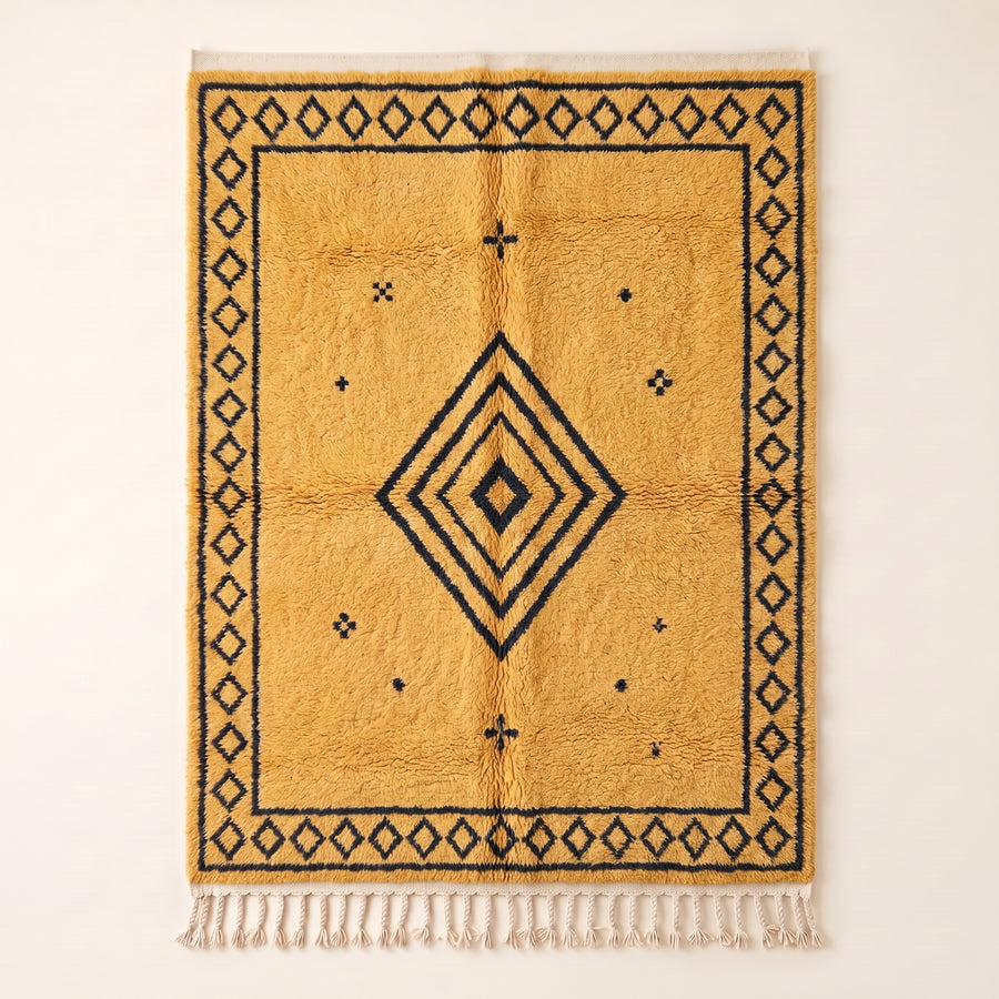 Saffron and charcoal Beni Ourain rug with concentric diamond motif, flat lay on plain background