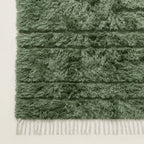 Corner detail of Tawenza rug showing cream wool fringe and horizontal banding on sage green field