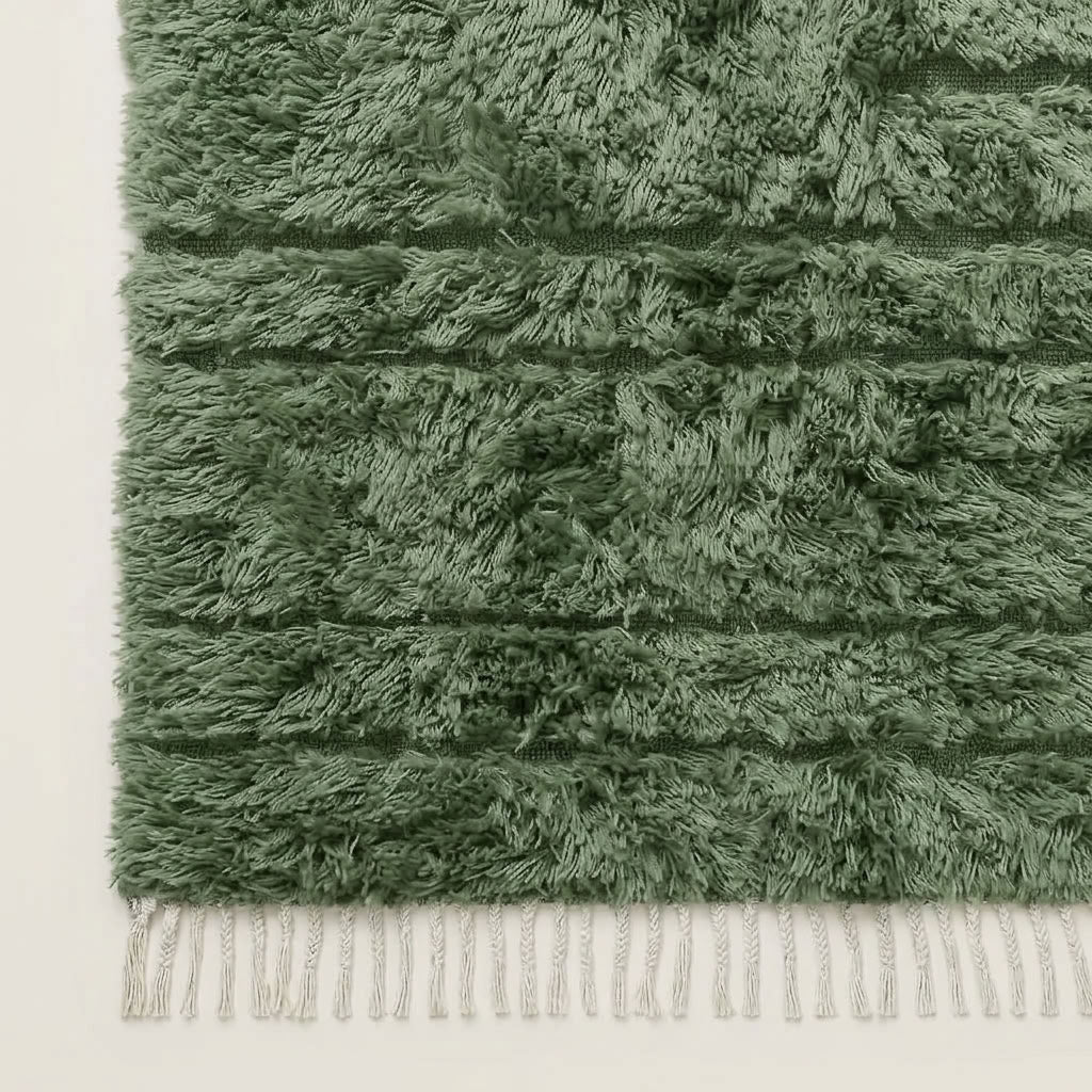 Corner detail of Tawenza rug showing cream wool fringe and horizontal banding on sage green field