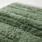 Close-up detail of Tawenza rug pile showing sage green and cream wool texture and depth