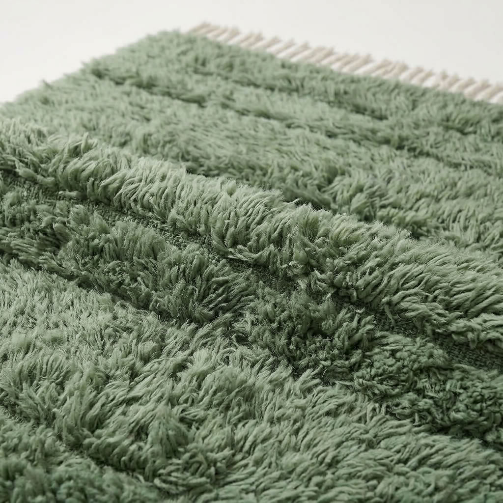 Close-up detail of Tawenza rug pile showing sage green and cream wool texture and depth