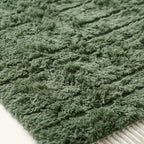 Macro view of Beni Ourain handwoven pile showing organic sage green and cream wool fibers