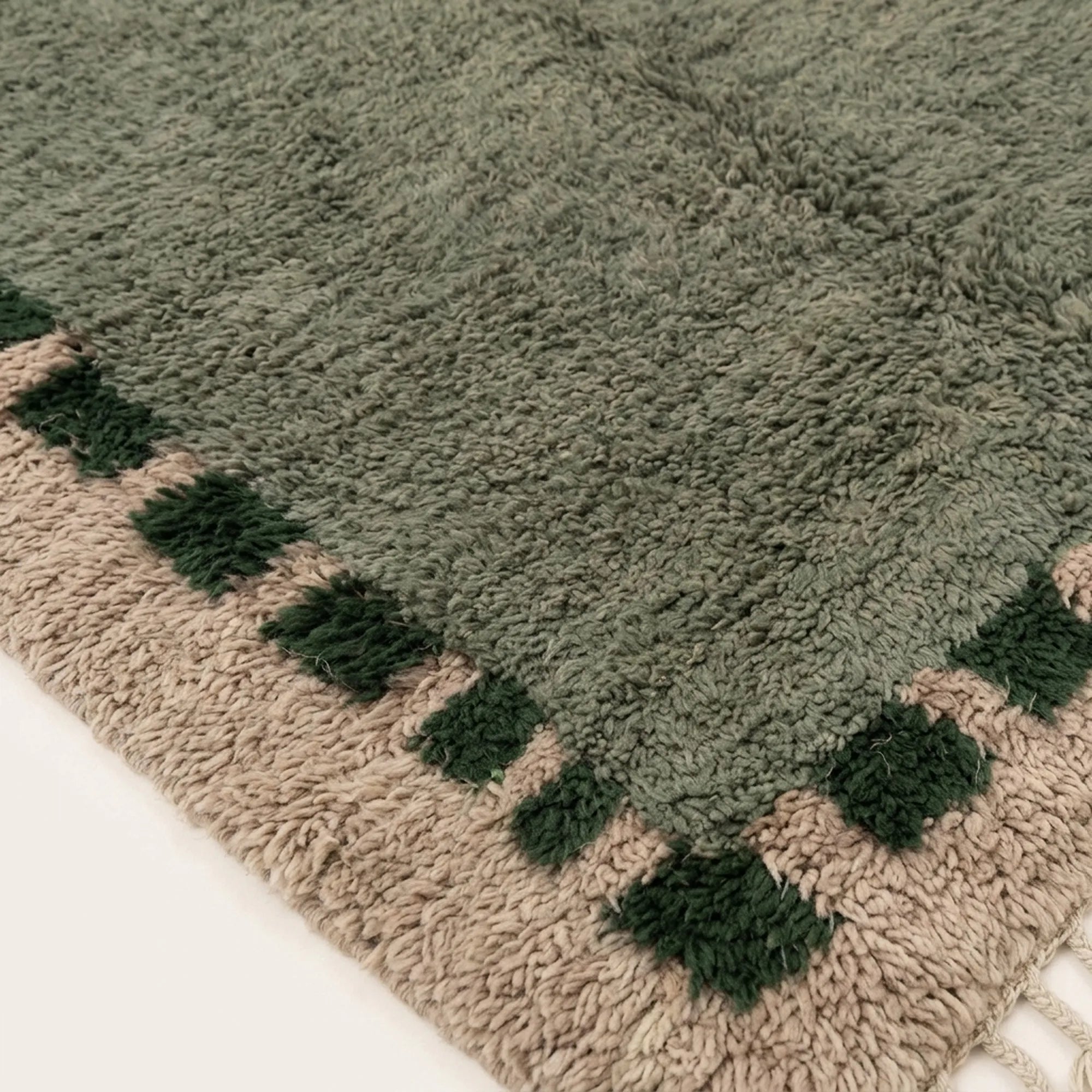 Close-up of the sage and forest green block border pattern on the Ifru ivory Beni Ourain rug.