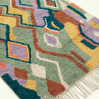 Lower edge detail of Tafrar showing sage, terracotta and lilac geometric motifs beside the wool fringe