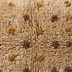 Close-up of the mustard freckle pattern on the Tazwit Moroccan wool pillow