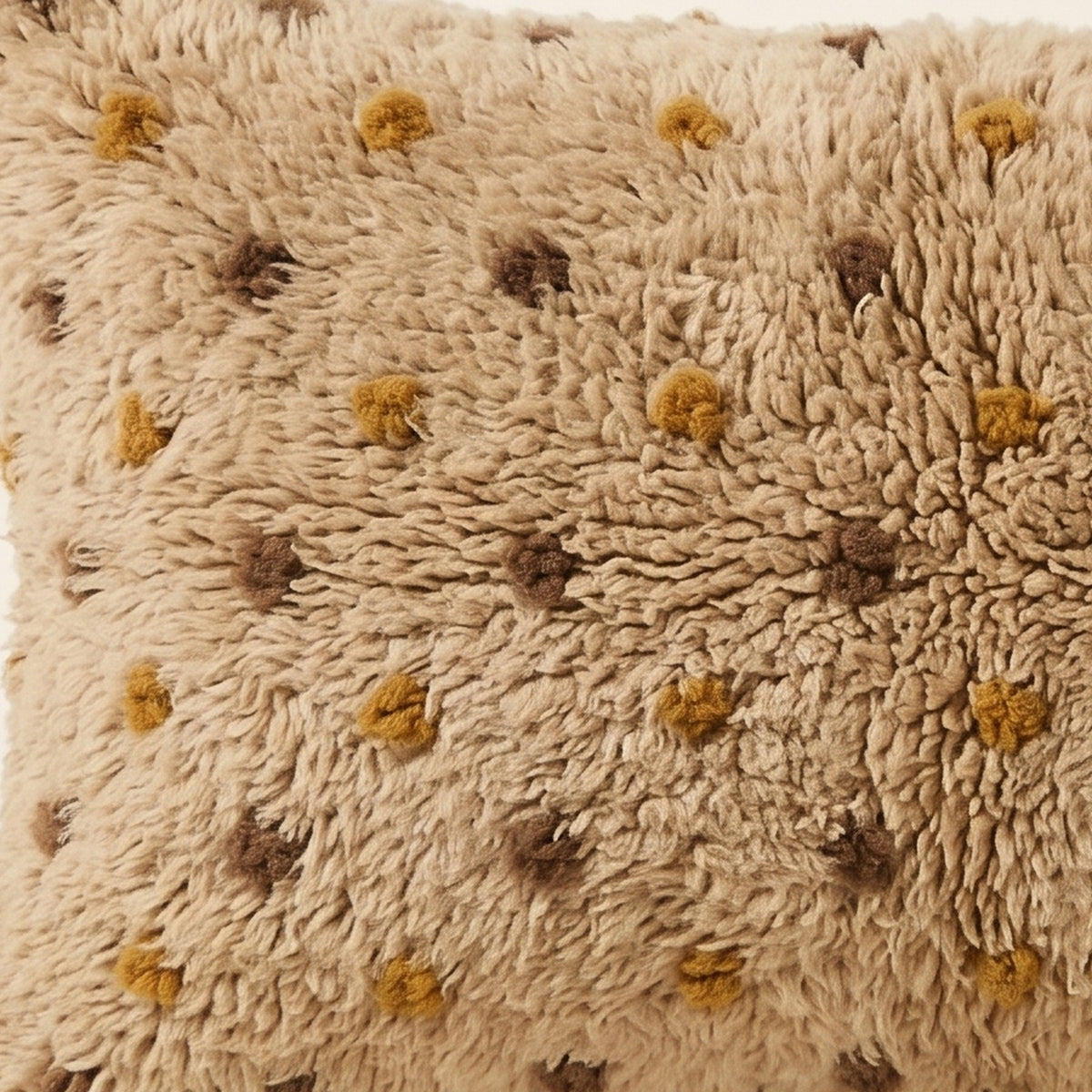 Side view of the Tazwit Moroccan pillow showing its sand and mustard wool pile