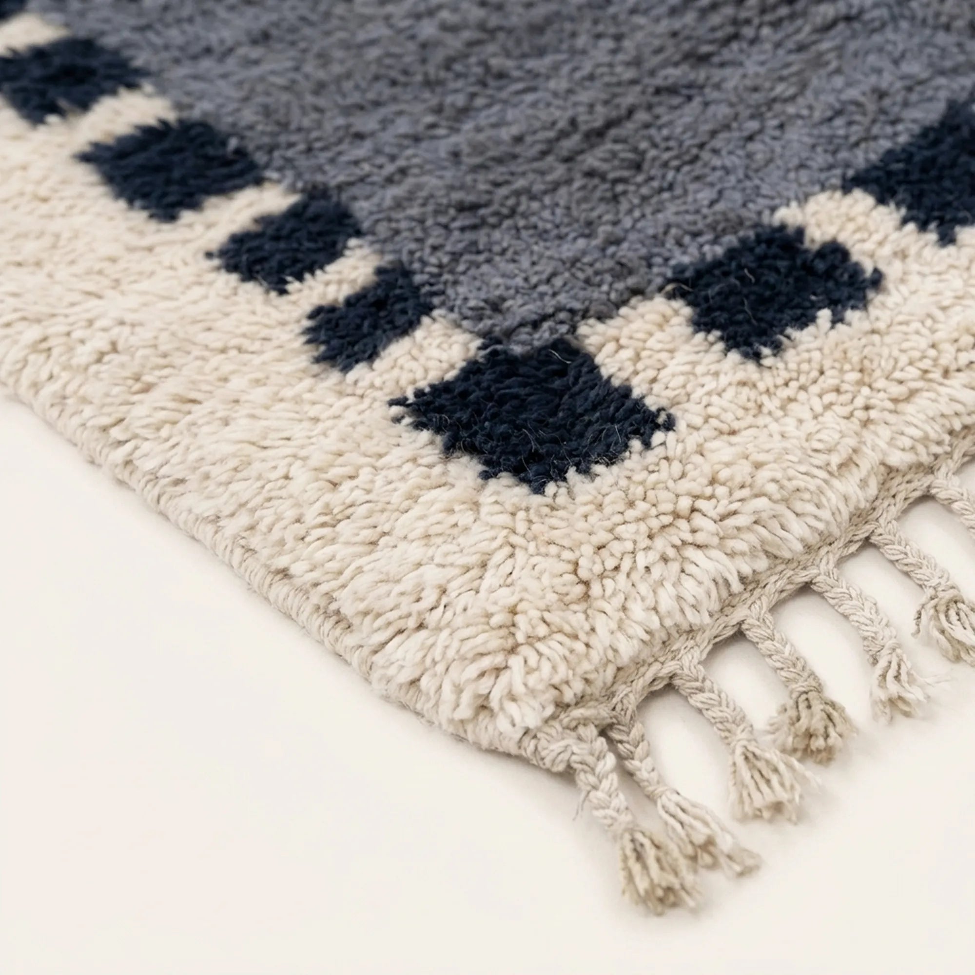 Close-up of the slate blue and navy block border pattern on the Tamesna ivory Beni Ourain rug.