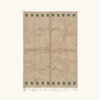 Full view of the Tala ivory Beni Ourain rug with a deep green border block motif and hand-tied fringe.