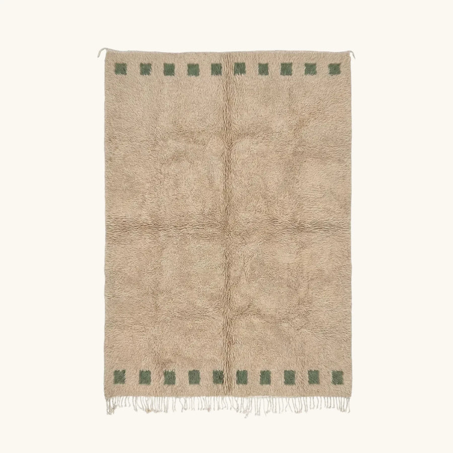 Full view of the Tala ivory Beni Ourain rug with a deep green border block motif and hand-tied fringe.