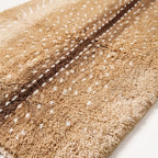 Close-up of plush knotted pile showing tan, chocolate and ivory spot pattern texture