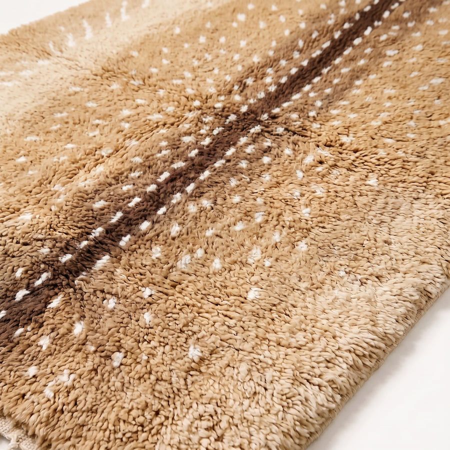 Close-up of plush knotted pile showing tan, chocolate and ivory spot pattern texture