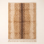 Tan and chocolate Beni Ourain rug with scattered ivory spots, flat lay on plain background