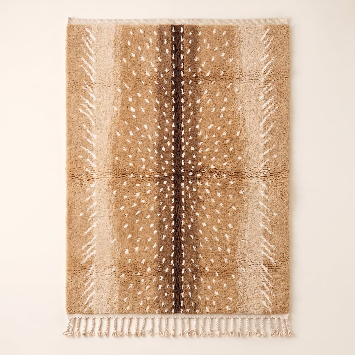 Tan and chocolate Beni Ourain rug with scattered ivory spots, flat lay on plain background