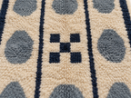 Close-up of plush pile showing slate blue pebbles, navy stripes and tan ground with textured knot detail