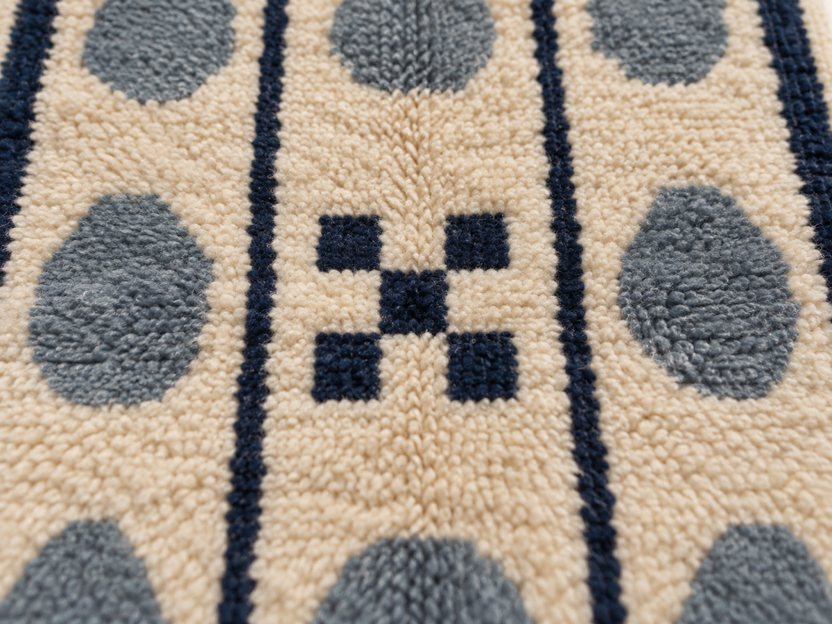 Close-up of plush pile showing slate blue pebbles, navy stripes and tan ground with textured knot detail