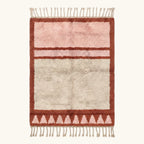 Full view of the Tanirt blush Beni Ourain rug with a framed triangle motif and hand-tied fringe.