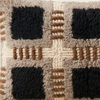 Side view of the Tifinagh Moroccan pillow showing its taupe, black and rust wool pile