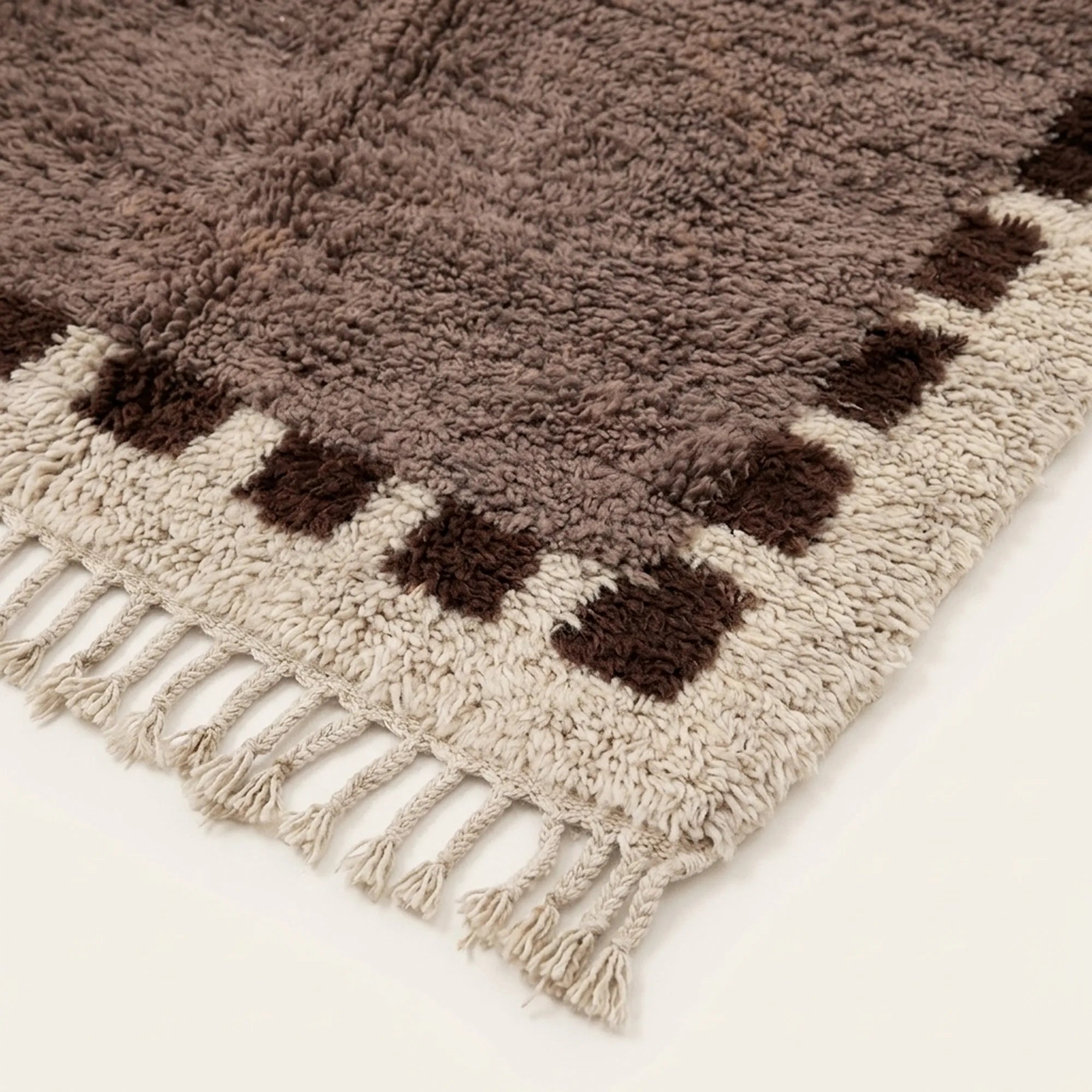 Close-up of the taupe and brown block border pattern on the Awrir ivory wool rug.