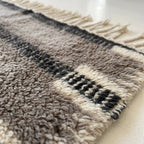 Close-up of the taupe and charcoal horizontal band pattern on the Aksel ivory wool rug.
