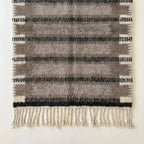 Angled view of the Aksel taupe, charcoal and ivory hand-knotted Beni Ourain rug.