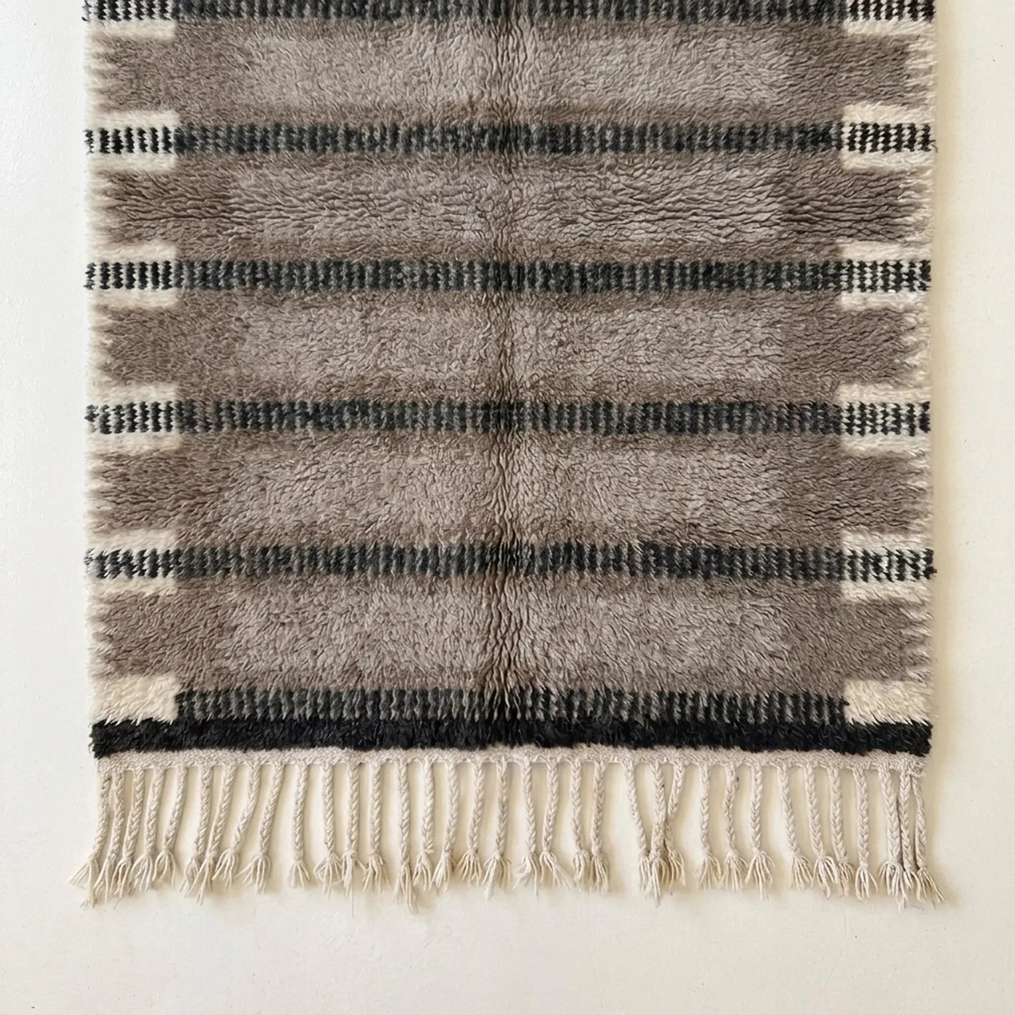 Angled view of the Aksel taupe, charcoal and ivory hand-knotted Beni Ourain rug.