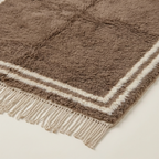 Corner and hand-tied fringe detail of the Ayyur taupe and ivory wool rug.