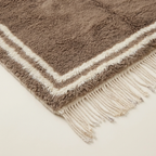 Angled corner view showing the ivory border of the Ayyur taupe rug.
