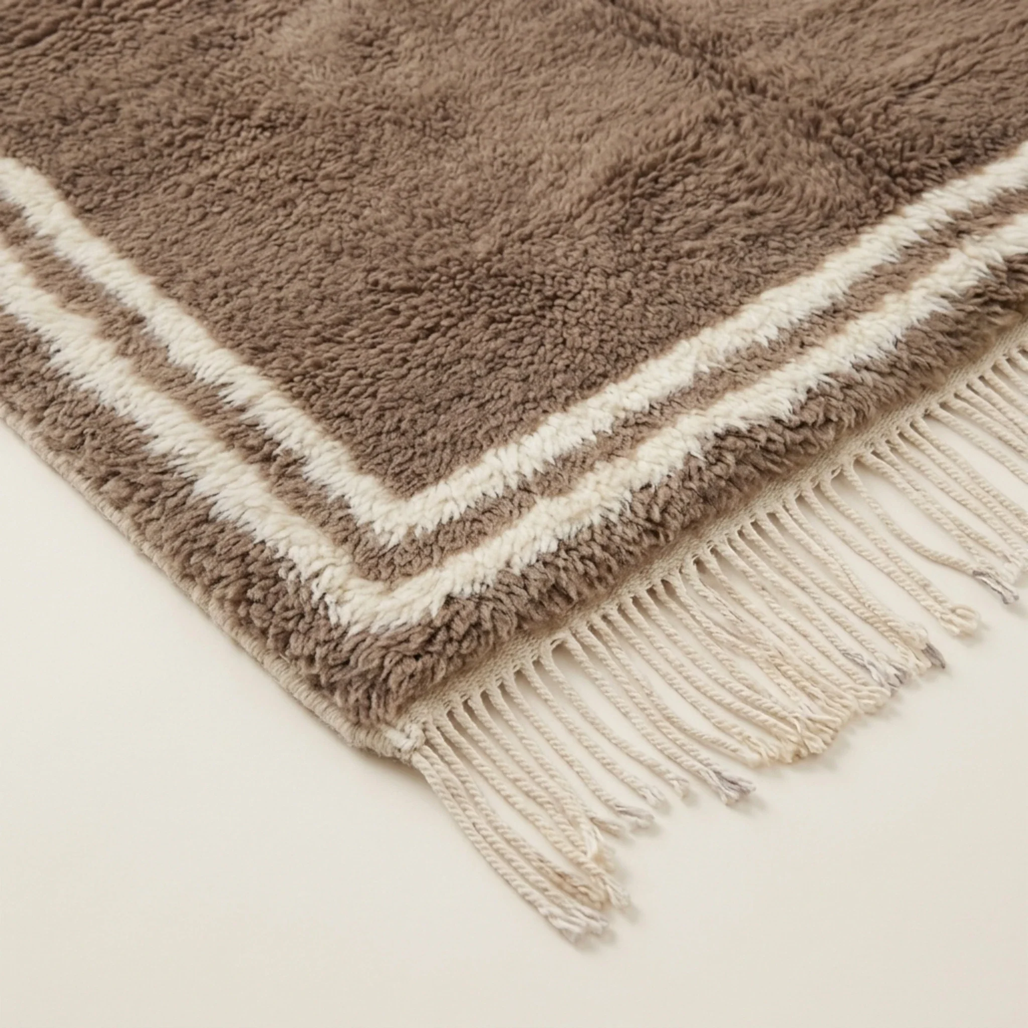 Angled corner view showing the ivory border of the Ayyur taupe rug.
