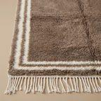 Ivory double border and fringe craftsmanship on the Ayyur taupe wool rug.