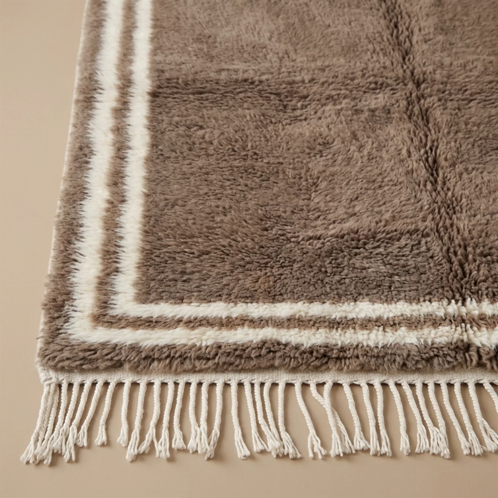 Ivory double border and fringe craftsmanship on the Ayyur taupe wool rug.