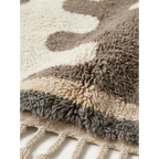 Fringe corner of the Tazrout taupe and ivory Beni Ourain rug showing its thick hand-knotted pile.