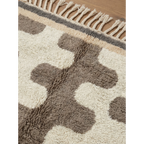 Pattern detail of the Tazrout Beni Ourain rug with sculptural taupe forms on an ivory wool field.