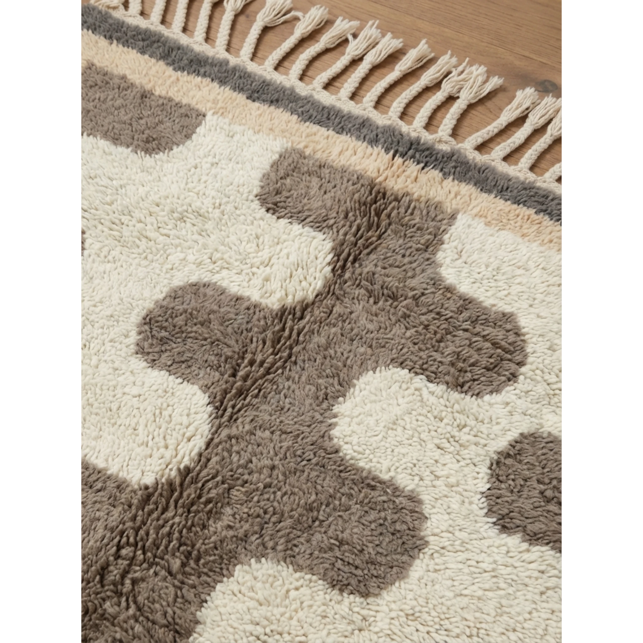 Pattern detail of the Tazrout Beni Ourain rug with sculptural taupe forms on an ivory wool field.