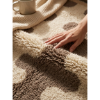 Hand touching the soft high-pile wool of the Tazrout taupe and ivory Beni Ourain rug.