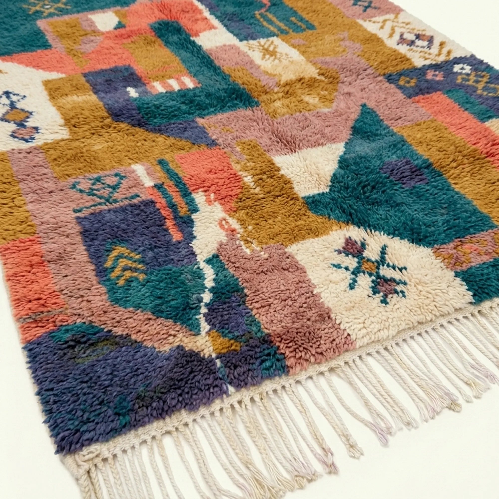Angled view of Tazmara showing teal, coral and ochre patchwork shapes and wool fringe