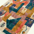 Close-up of the Tazmara Boujaad rug showing layered geometric patchwork and small woven symbols